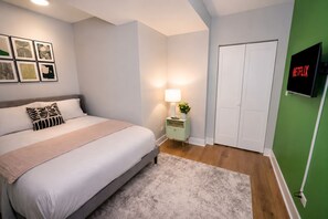 A bedroom with a bed, bedside table, lamp, and a wall-mounted TV.