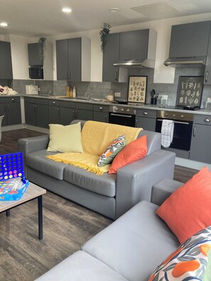 Ein modernes Wohnzimmer mit einem grauen Sofa, einem Couchtisch und einem Gesellschaftsspiel.