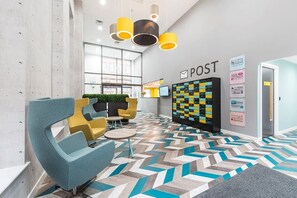 A modern lobby with a herringbone patterned floor, a reception desk, and a wall-mounted information board. - Student Only Bentley House (Birmingham)