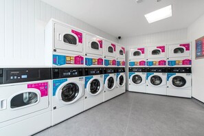 A laundry facility with multiple washing machines and dryers, arranged in rows. - Student Only Bentley House (Birmingham)