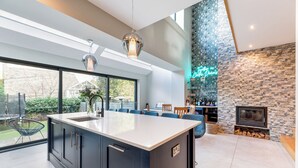 Una cocina moderna con una isla grande, un muro decorativo de piedra, una chimenea y una zona de bar.