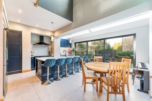Una cocina moderna con una isla central, taburetes de bar y una mesa de comedor con sillas.