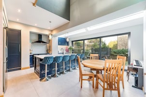 Una cocina moderna con una isla central, taburetes de bar y una mesa de comedor con sillas.