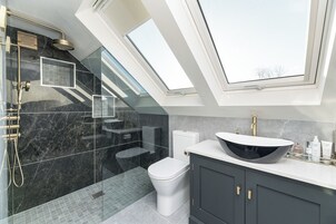 Un baño moderno con tragaluz, una bañera independiente y un tocador con un lavabo grande.