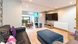 Una sala de estar moderna con un sofá, reposapiés y un televisor montado en la pared.