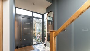 Un pasillo moderno con suelo de diseño geométrico, una escalera de madera y un espejo grande.