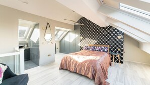 Un dormitorio moderno con tragaluces, una cama con cabecera estampada y un armario empotrado.