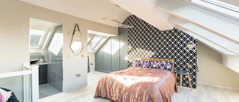A modern bedroom with a skylight, a bed with a patterned headboard, and a built-in wardrobe.