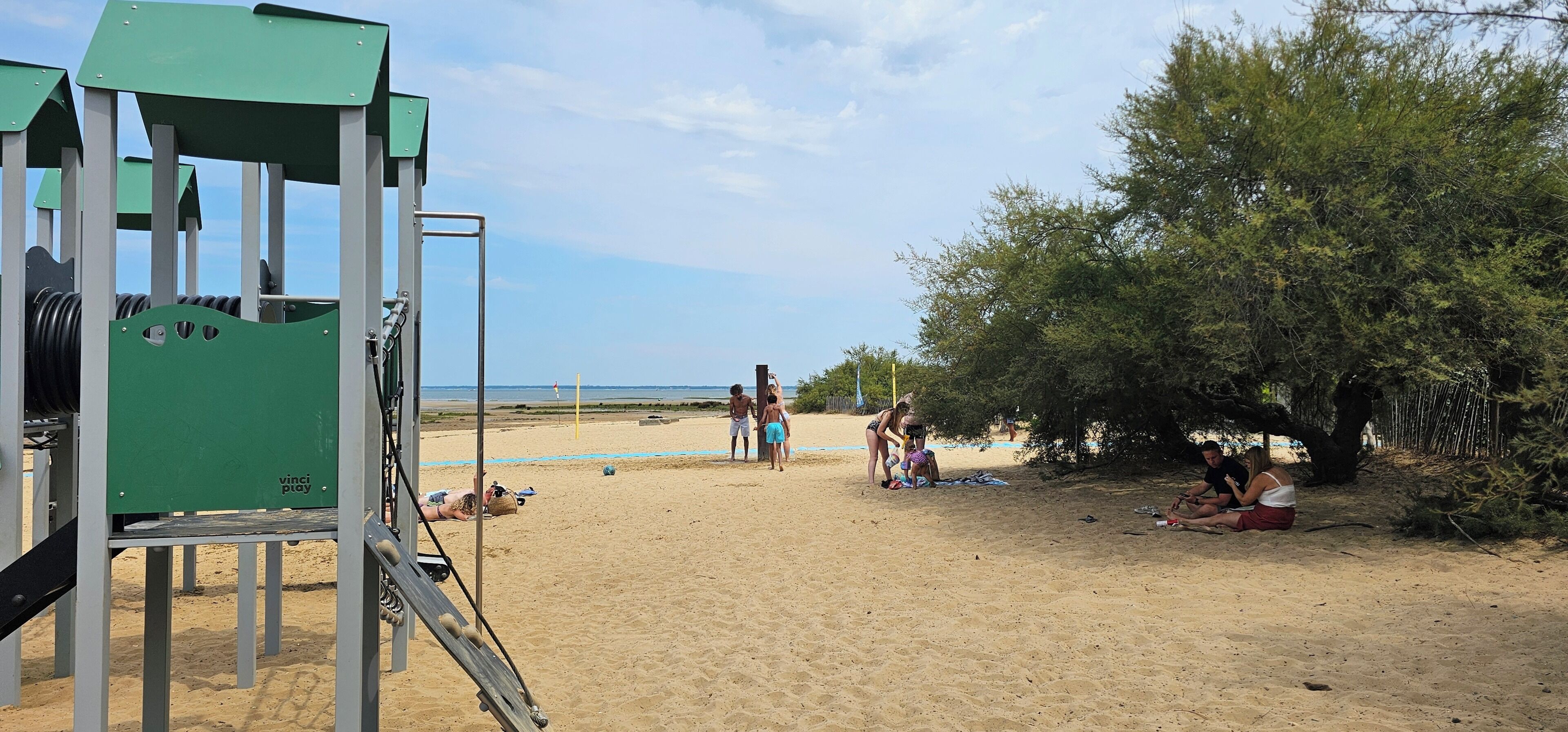 A sandy beach with a lifeguard tower, beach umbrellas, and people relaxing.