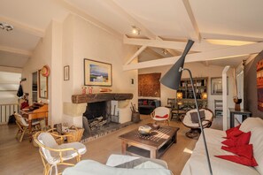 A spacious living room with a fireplace, comfortable seating, and a bookshelf. - Between the ocean and the Bassin, near the tip, house with large garden (Lège-Cap-Ferret)