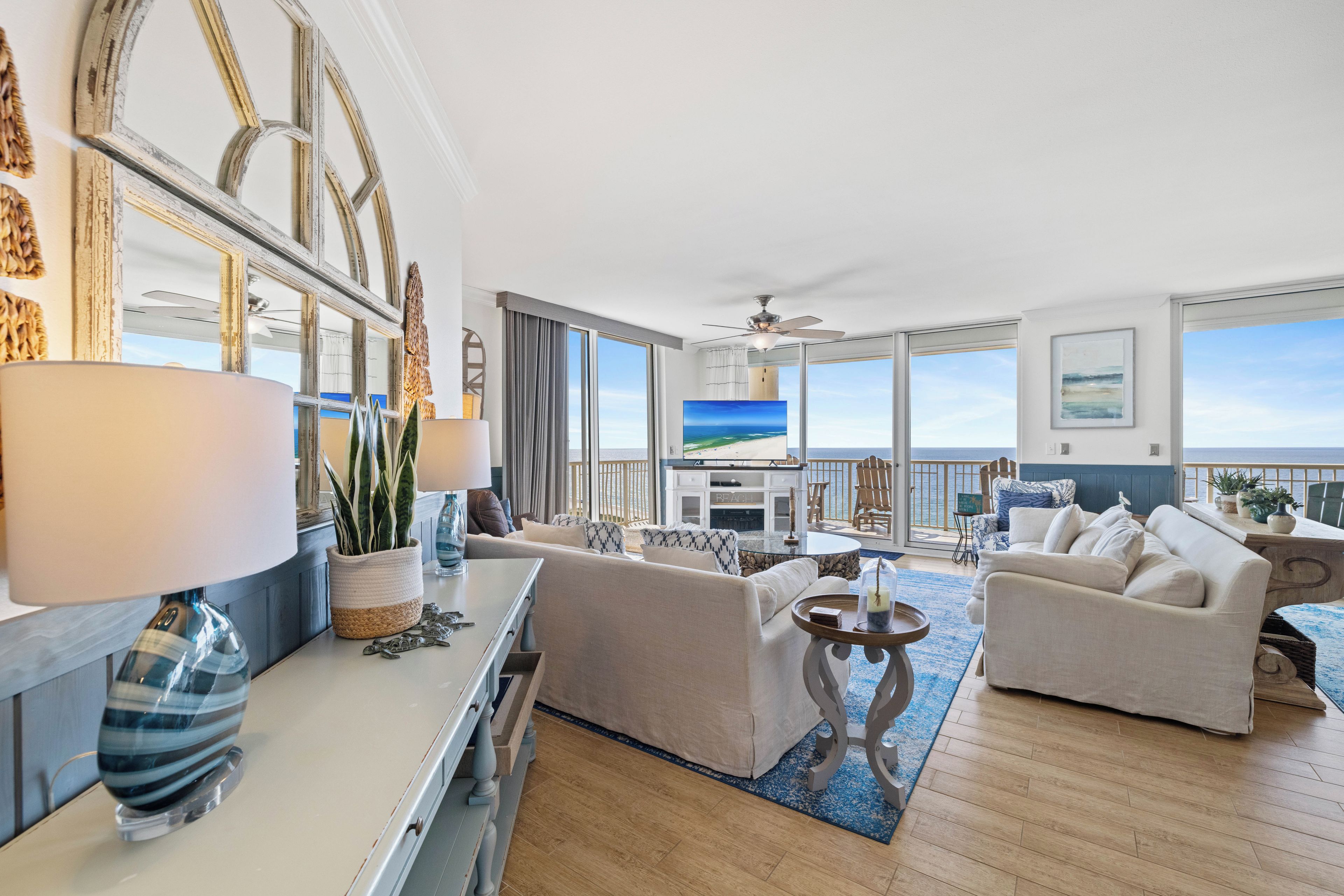 A spacious living room with a large TV, comfortable seating, and a view of the ocean.