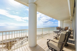 Ein Balkon mit Gartenmöbeln, der auf einen Strand und das Meer blickt.