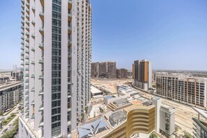 Um edifício alto com várias varandas, um canteiro de obras em primeiro plano e outros edifícios ao fundo.