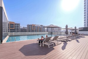Ein Poolbereich auf dem Dach mit Liegestühlen, einem Schwimmbecken und Blick auf die Stadt.