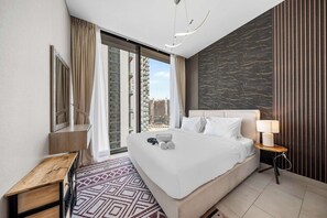 Ein modernes Hotelzimmer mit einem großen Bett, einem Schreibtisch, einer Lampe und Blick auf die Stadt.