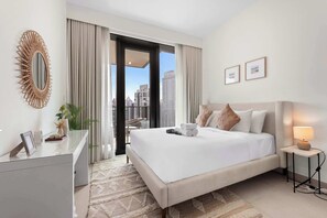 Ein Hotelzimmer mit Bett, Nachttisch mit Lampe, Spiegel und Blick auf die Stadt.