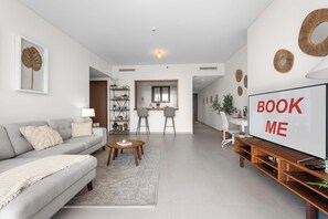 Ein modernes Wohnzimmer mit Sofa, Couchtisch, Fernseher und einem Schild mit der Aufschrift 'BOOK ME'.