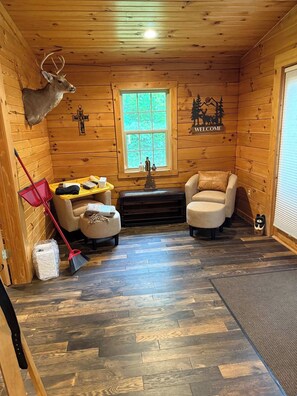 A cozy cabin interior with wooden walls, a fireplace, a bench, and a deer head decoration.
