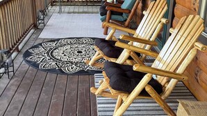 A wooden deck with outdoor seating, a table, and a lantern.