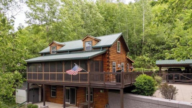 A log cabin with a balcony, a flag, and a stone wall.