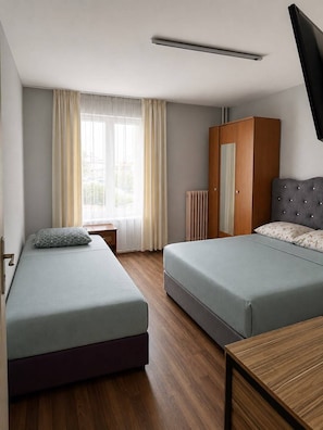 Habitación de hotel con dos camas, un armario, un radiador y un televisor.
