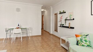 Een eetgedeelte met een tafel en stoelen, een bank en een gang die naar een andere kamer leidt.