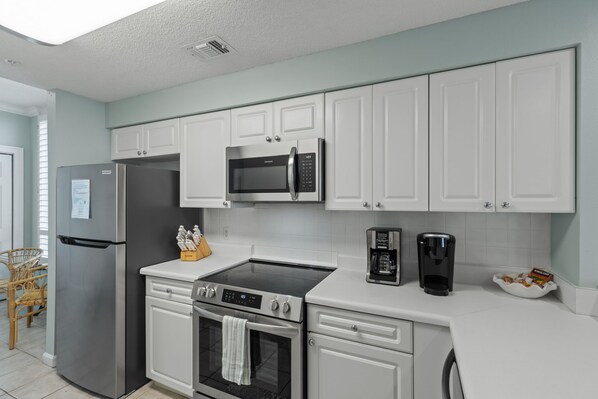 A modern kitchen with white cabinets, stainless steel appliances, and a built-in oven. - Dog Friendly | Gulf Front | Heated Pool | Hot tub (Navarre)