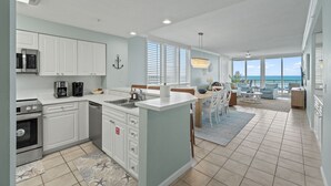 A modern kitchen with white cabinetry, a built-in microwave, and a coffee maker.