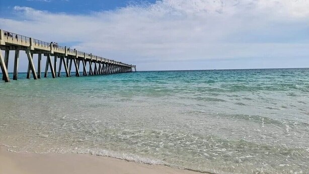 A pier extending into calm waters with clear skies.