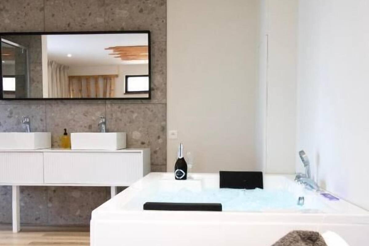 Une salle de bain moderne avec une grande baignoire, un meuble-lavabo à deux vasques et un miroir au-dessus du meuble-lavabo.