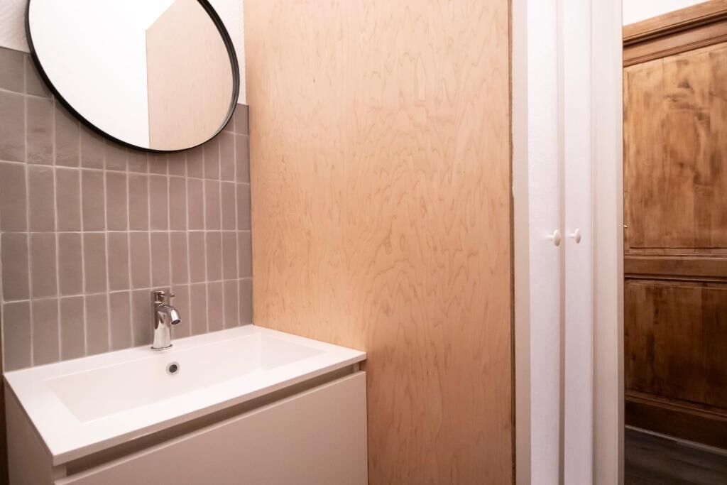 A bathroom with a white sink, a mirror, and a wooden door.