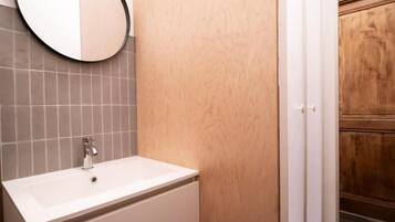 A bathroom with a white sink, a mirror, and a wooden door.