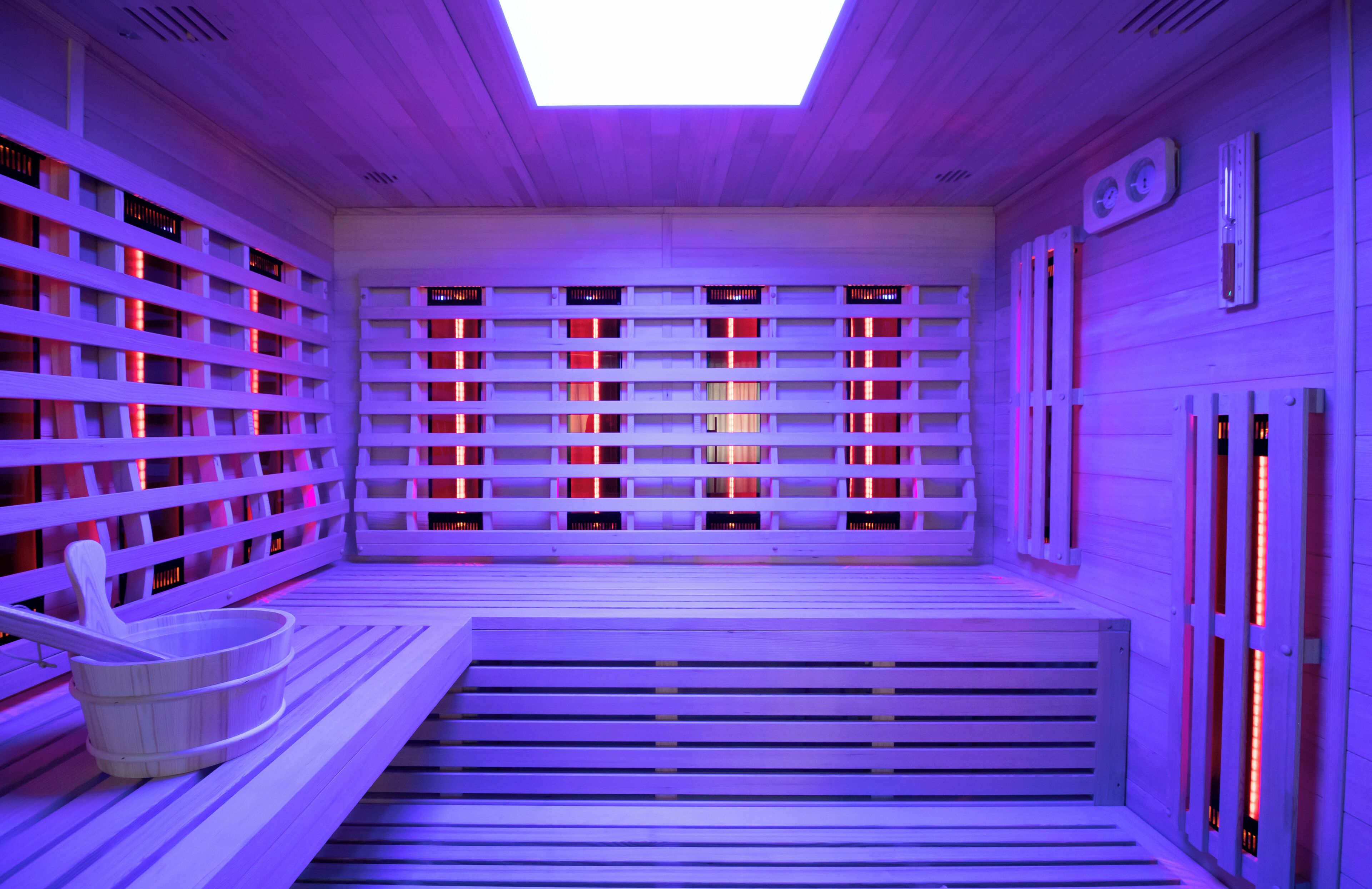Un sauna avec des bancs en bois, un plancher incliné et une lucarne.