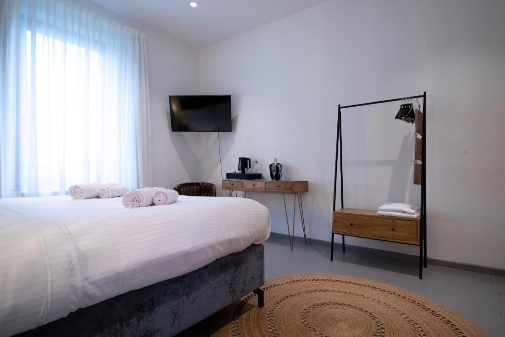 A bedroom with a bed, a TV, a wooden bench, and a mirror.