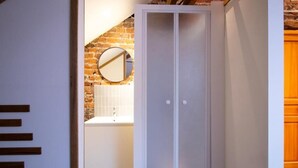 A bathroom with a white sink, a round mirror, and a white cabinet with frosted glass doors.