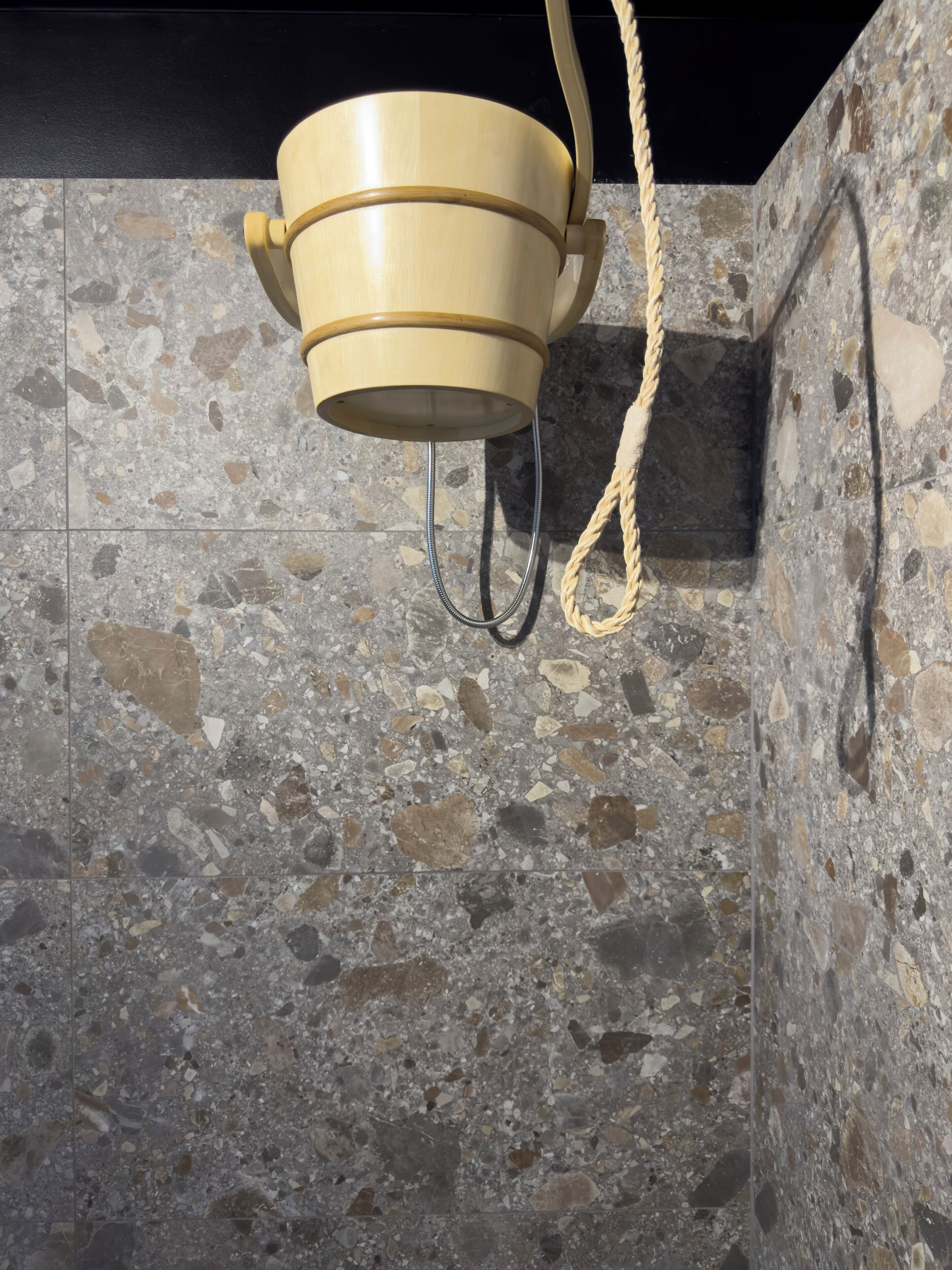 A stone wall with a hanging wooden bucket.