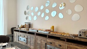 A modern kitchen with a breakfast bar, a wooden cabinet with drawers, and a wall-mounted mirror arrangement.
