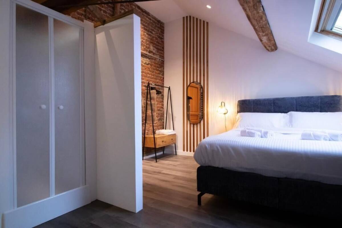 Une chambre à coucher avec un lit, une armoire, un miroir et un mur en bois.