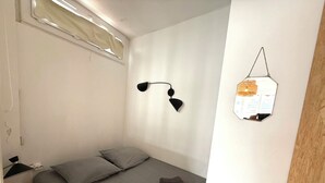 Ein Schlafzimmer mit einem Bett, einer Wandlampe, einem Spiegel und einer Holztür.
