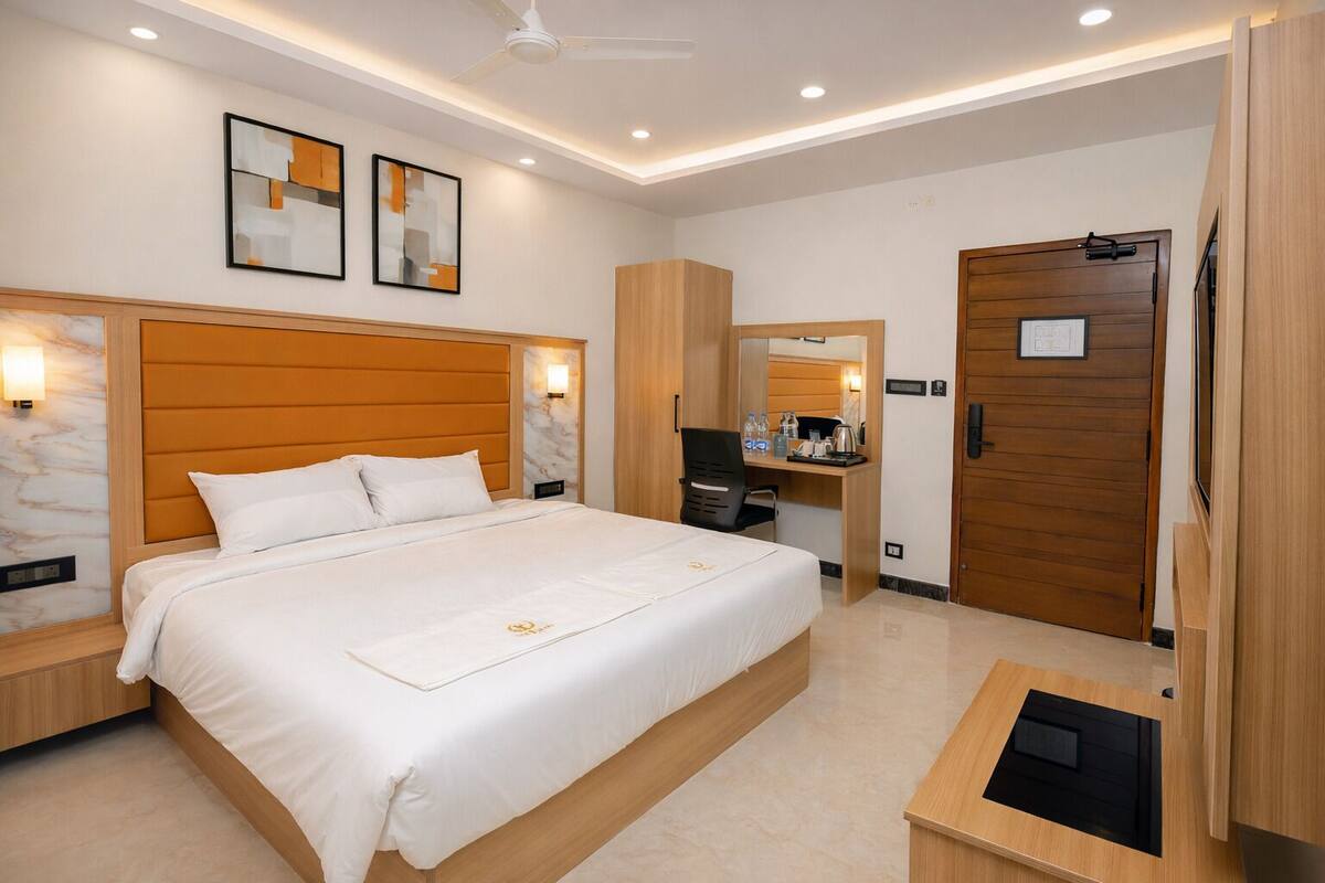 A hotel room with a large bed, a desk, a wardrobe, and a mirror.