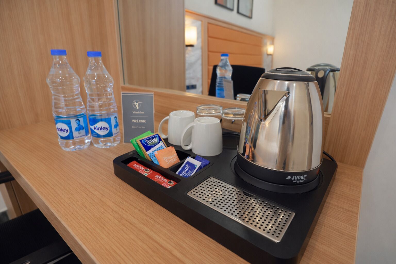 A hotel room's minibar with water bottles, coffee, tea, and a kettle.