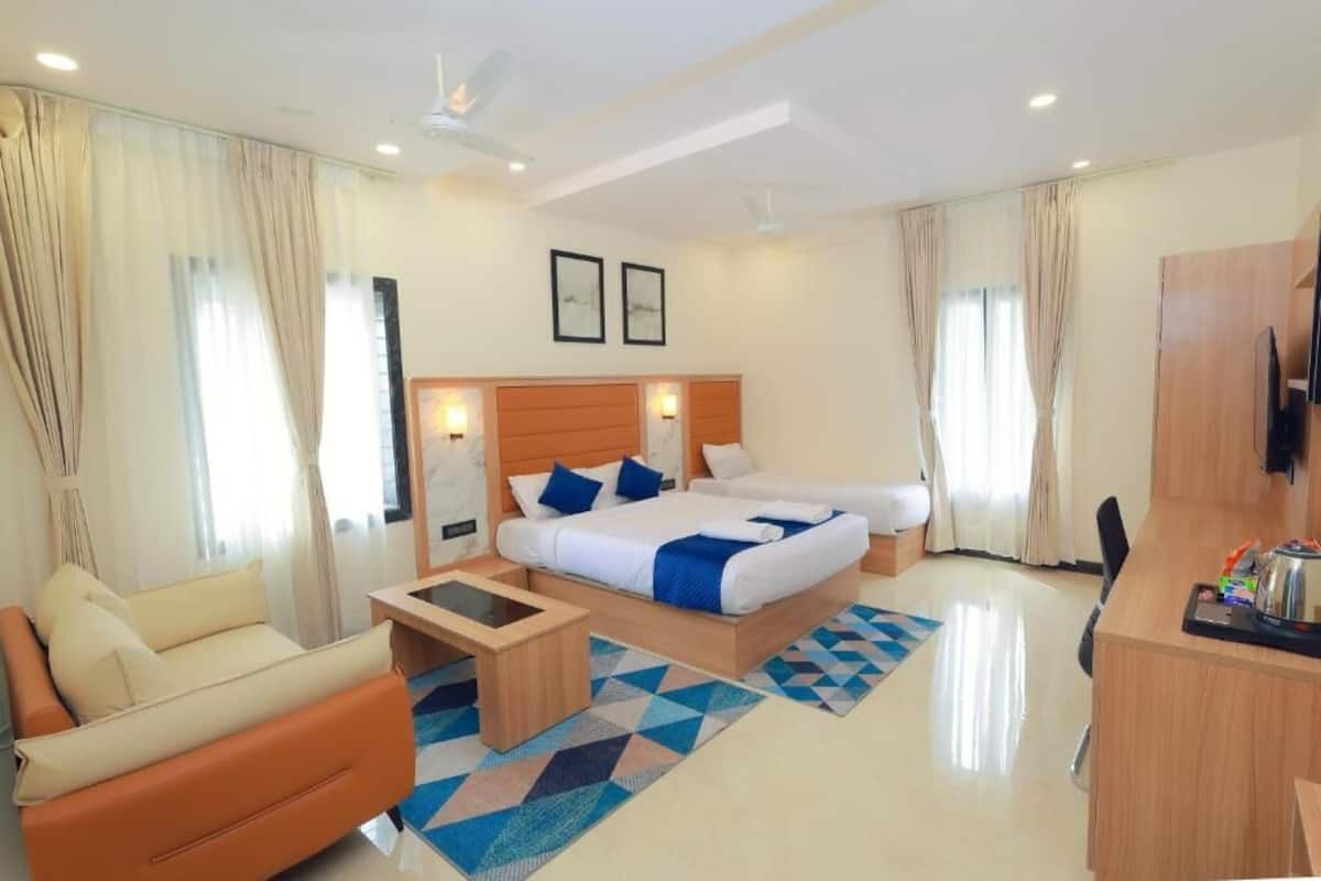 A hotel room with a bed, a sofa, a desk, and a TV.