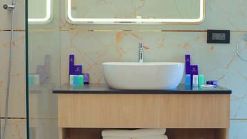 Un baño moderno con un lavamanos grande y blanco, un espejo con bordes iluminados y una cabina de ducha de vidrio.