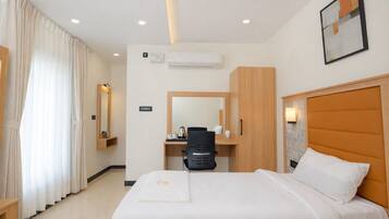 Quarto de hotel com cama, escrivaninha, cadeira, guarda-roupa e ar condicionado.