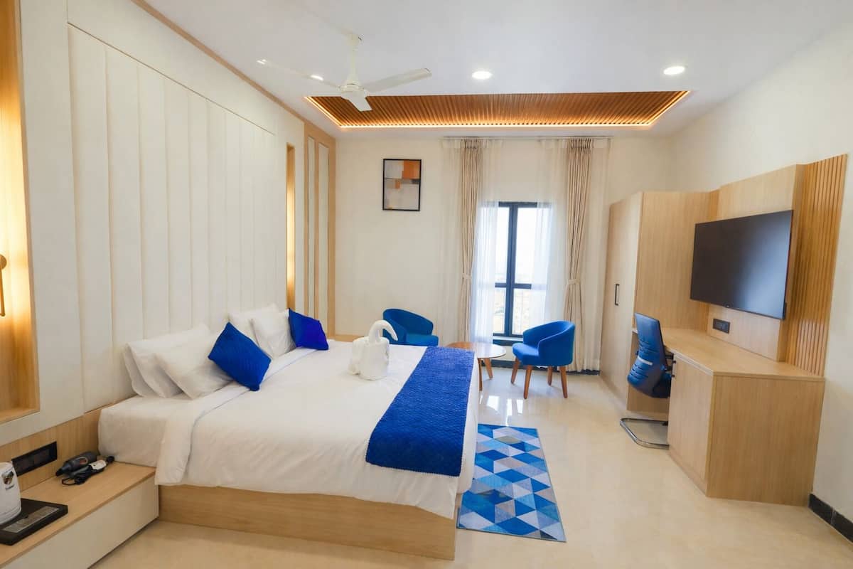 A hotel room with a bed, a desk, a chair, a TV, and a window.