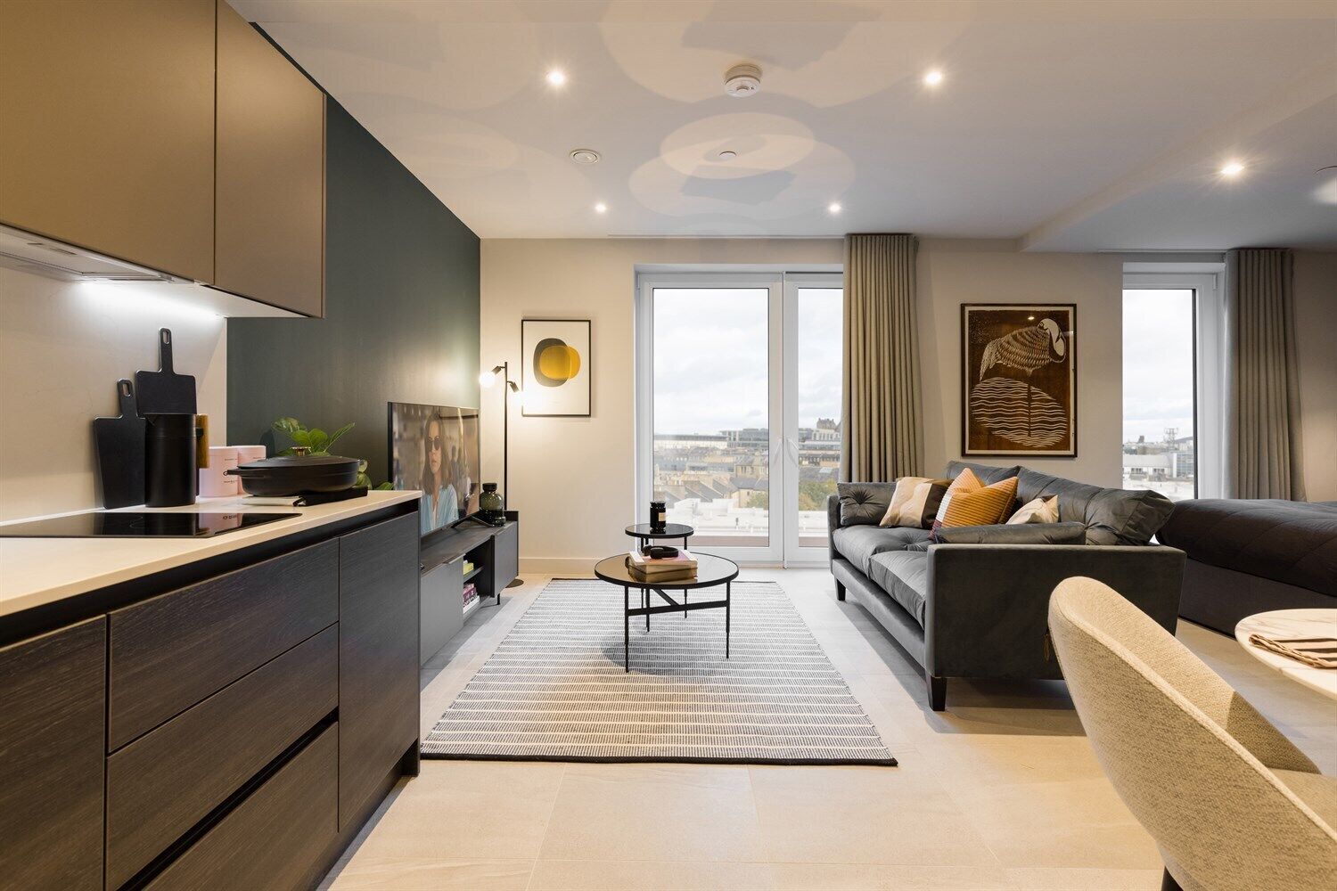 A modern apartment with a kitchen, living area, and large windows.