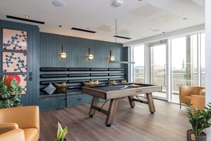 A modern room with a pool table, seating area, and large windows offering a city view. - The McEwan (Edinburgh)