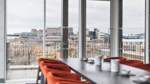 Ett modernt matområde med utsikt över stadsbilden genom stora fönster.
