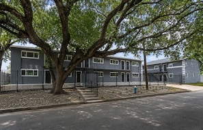 A multi-story residential building with a tree in front, a blue fire hydrant, and a black fence. - Elegant 1BR Near Downtown, Med Center, NRG & Astros (Houston)