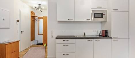 A modern kitchen with white cabinets, a microwave, and a coffee maker.